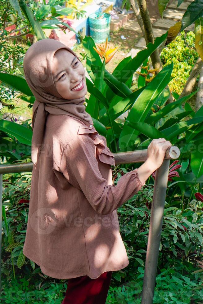 side view of a woman wearing a headscarf holding a safety iron for her hands with an expression facing the camera. photo