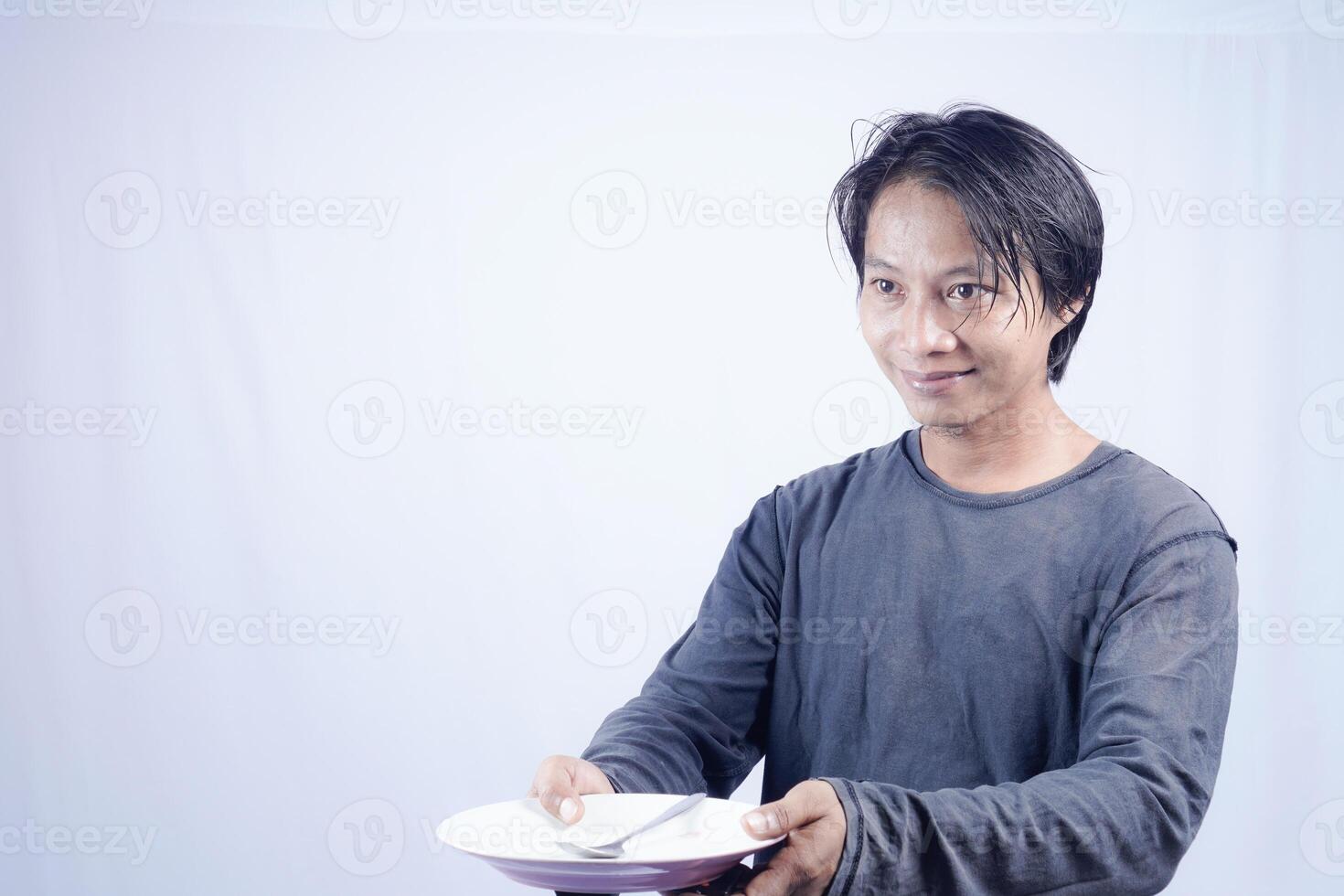 close up view of handsome asian man holding plate with happy expression, showing that the food is delicious on isolated white background for advertising. photo