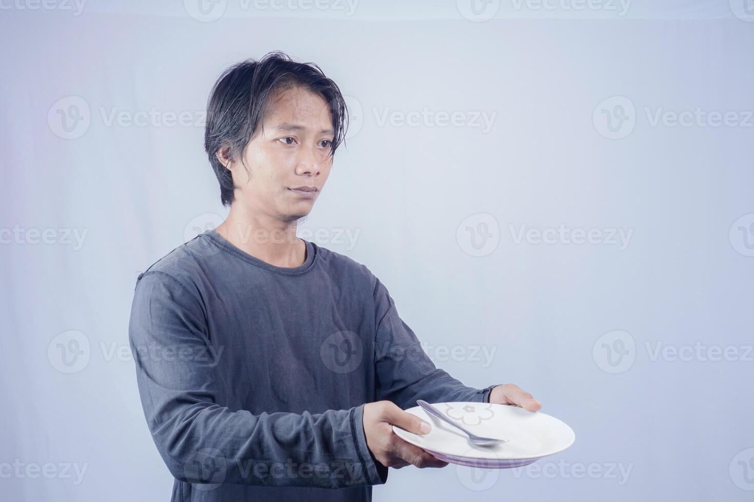 Portrait of Asian men who are hungry holding empty plates to ask to eat with a white background that is isolated for the photocopy space on it. Menu Poet Concept. photo