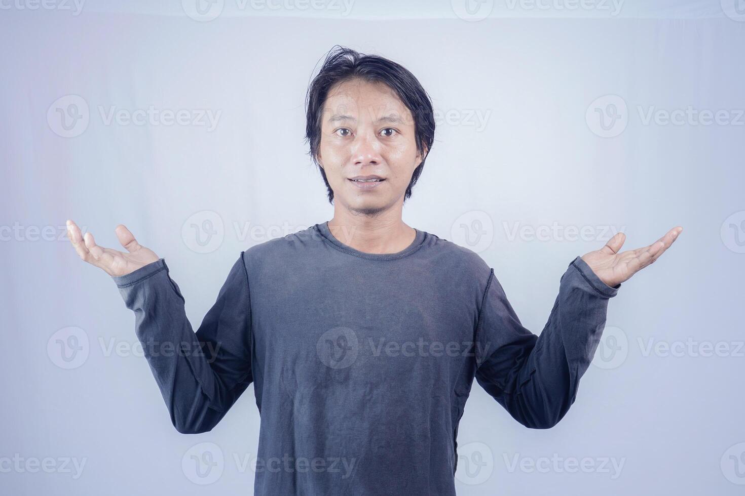 Handsome Asian man facing the camera is pointing at the copy space for advertising on an isolated white background. photo