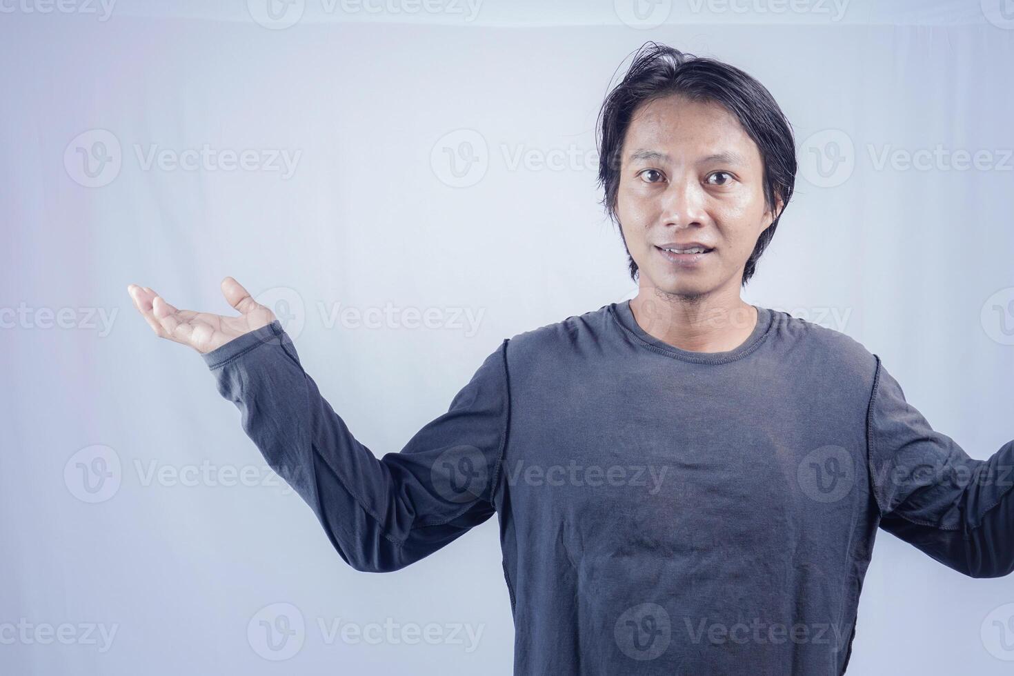 Handsome Asian man facing the camera is pointing at the copy space for advertising on an isolated white background. photo