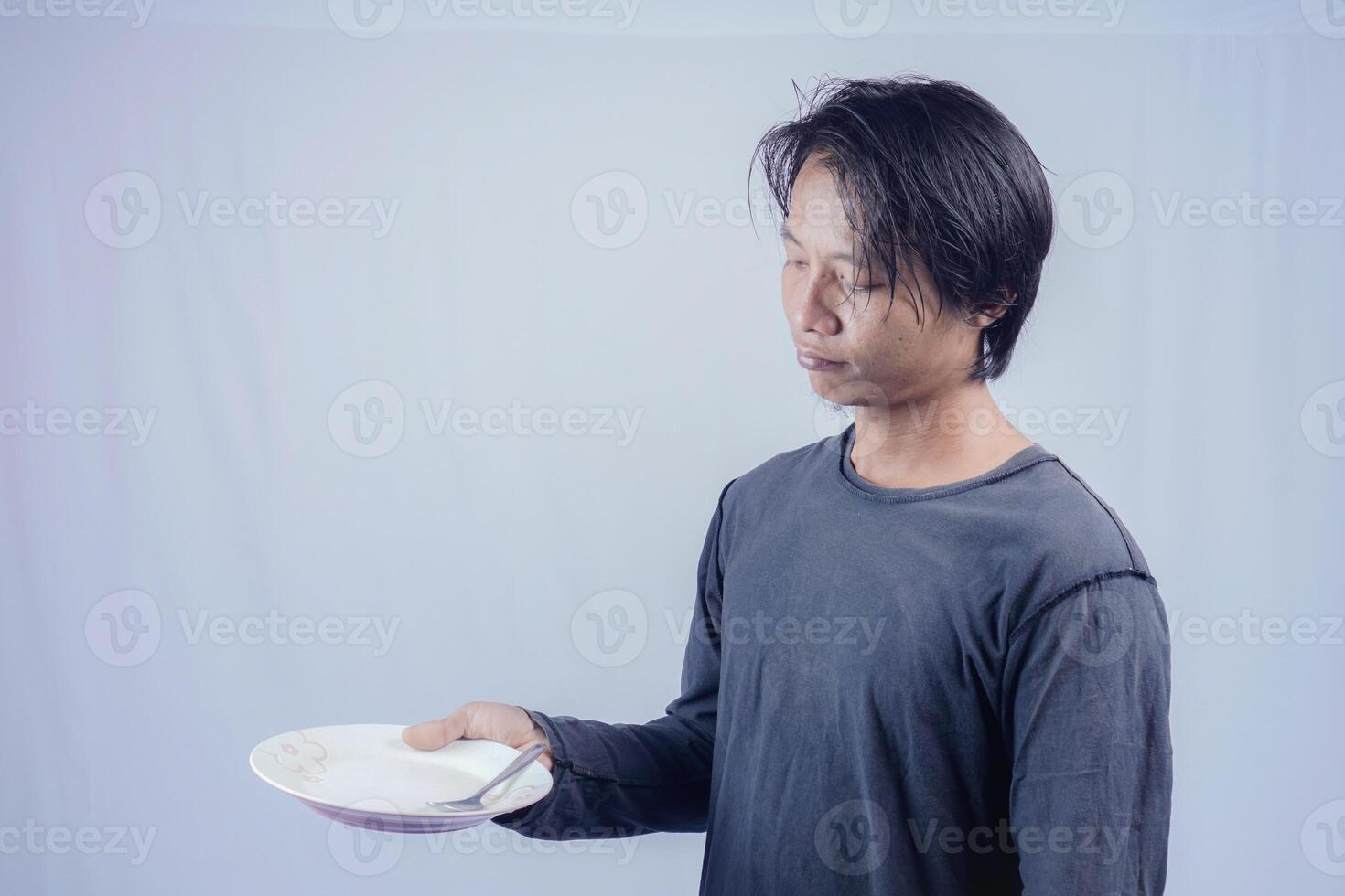 handsome asian man holding empty plate while thinking for serving food menu on isolated white background for advertising menu. menu presentation concept. photo