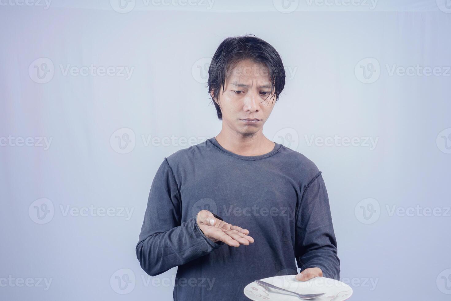 Portrait of Asian men who are hungry holding empty plates to ask to eat with a white background that is isolated for the photocopy space on it. Menu Poet Concept. photo