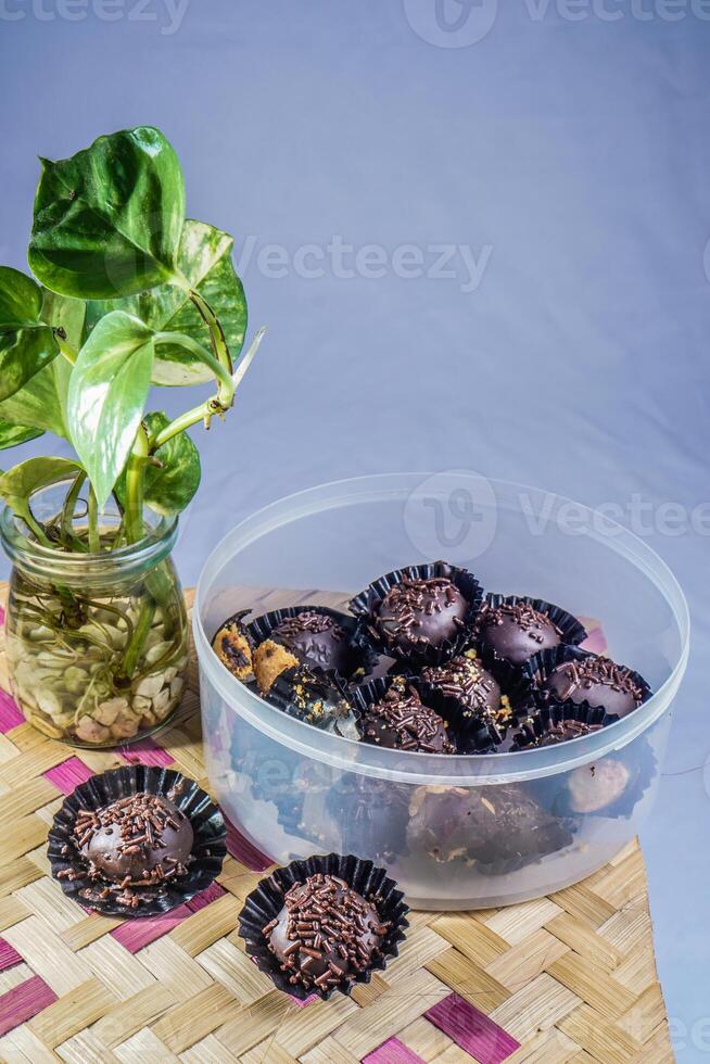 aislado chocolate albóndigas, de cerca ver de chocolate empanadillas rociado con asperja, con tejido bambú como un base y ornamental plantas en el lado. eid comida concepto. foto