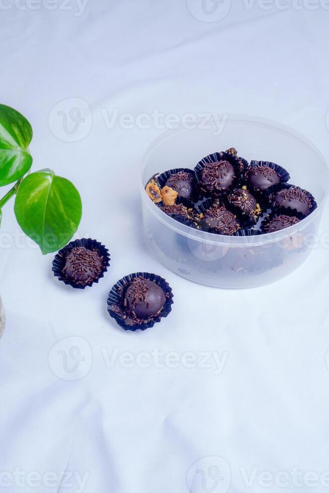 Trisolated chocolate ball cake, close-up view of chocolate ball cake sprinkled with lemongrass on a white background with decorative plants on the side. photo