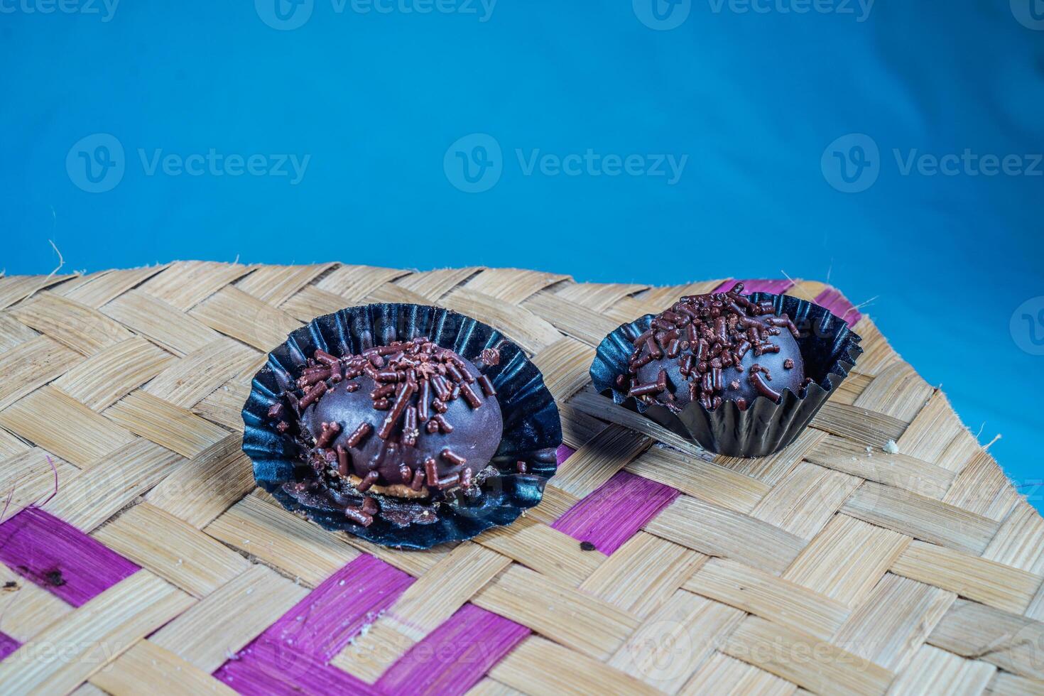 Isolated chocolate dumplings, close-up view of chocolate dumplings sprinkled with sprinkles, with woven bamboo as a base and ornamental plants on the side. Eid meal concept. photo