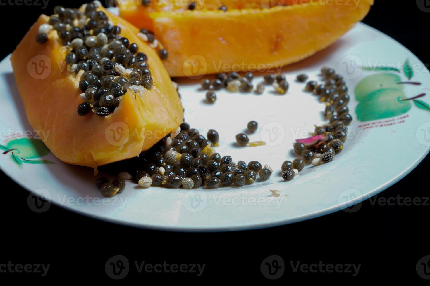 close up view of papaya fruit isolated on plate on black background. photo