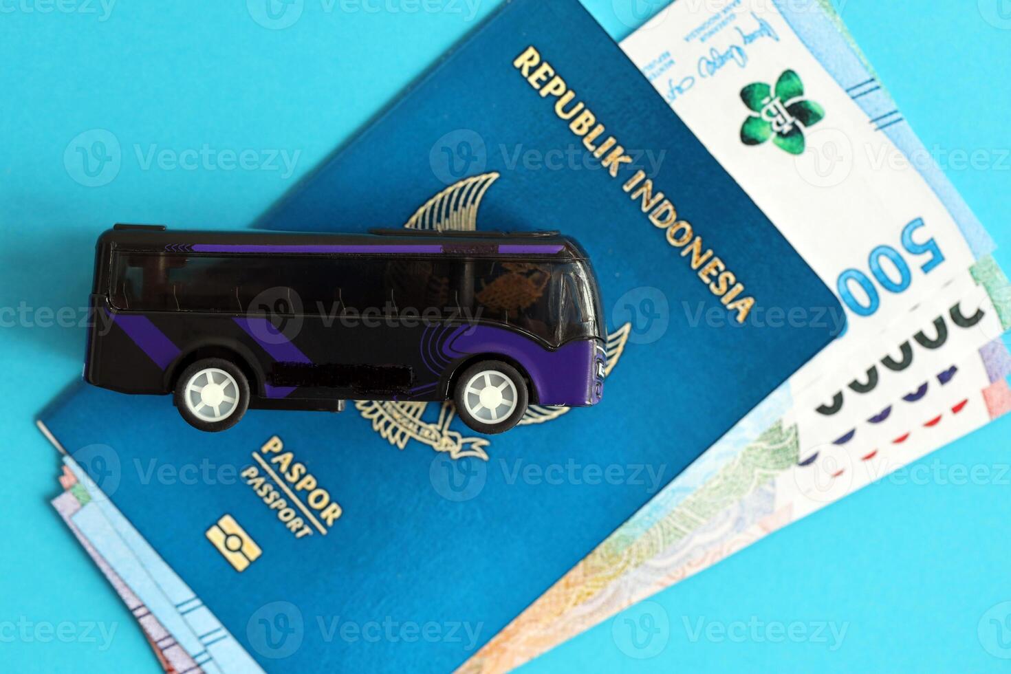 Blue Republic Indonesia passport with money and toy bus on blue background close up photo