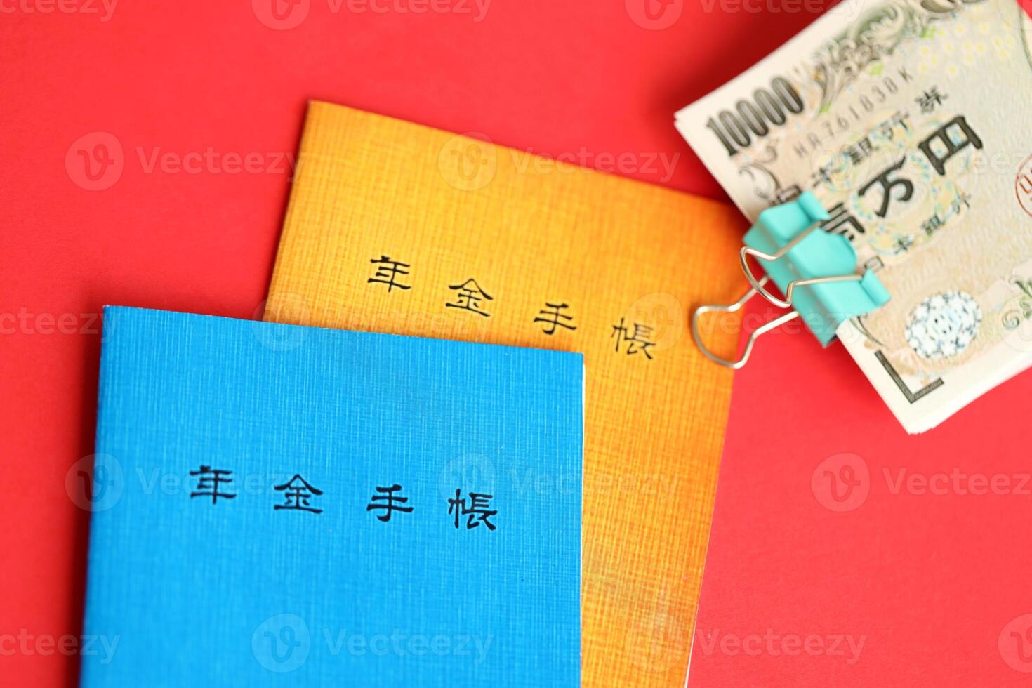 Japanese pension insurance booklets on table with yen money bills. Blue and orange books photo