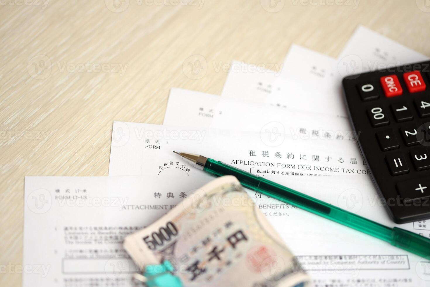 Japanese tax forms lies on table with calculator, pen and japanese yen money bills roll photo