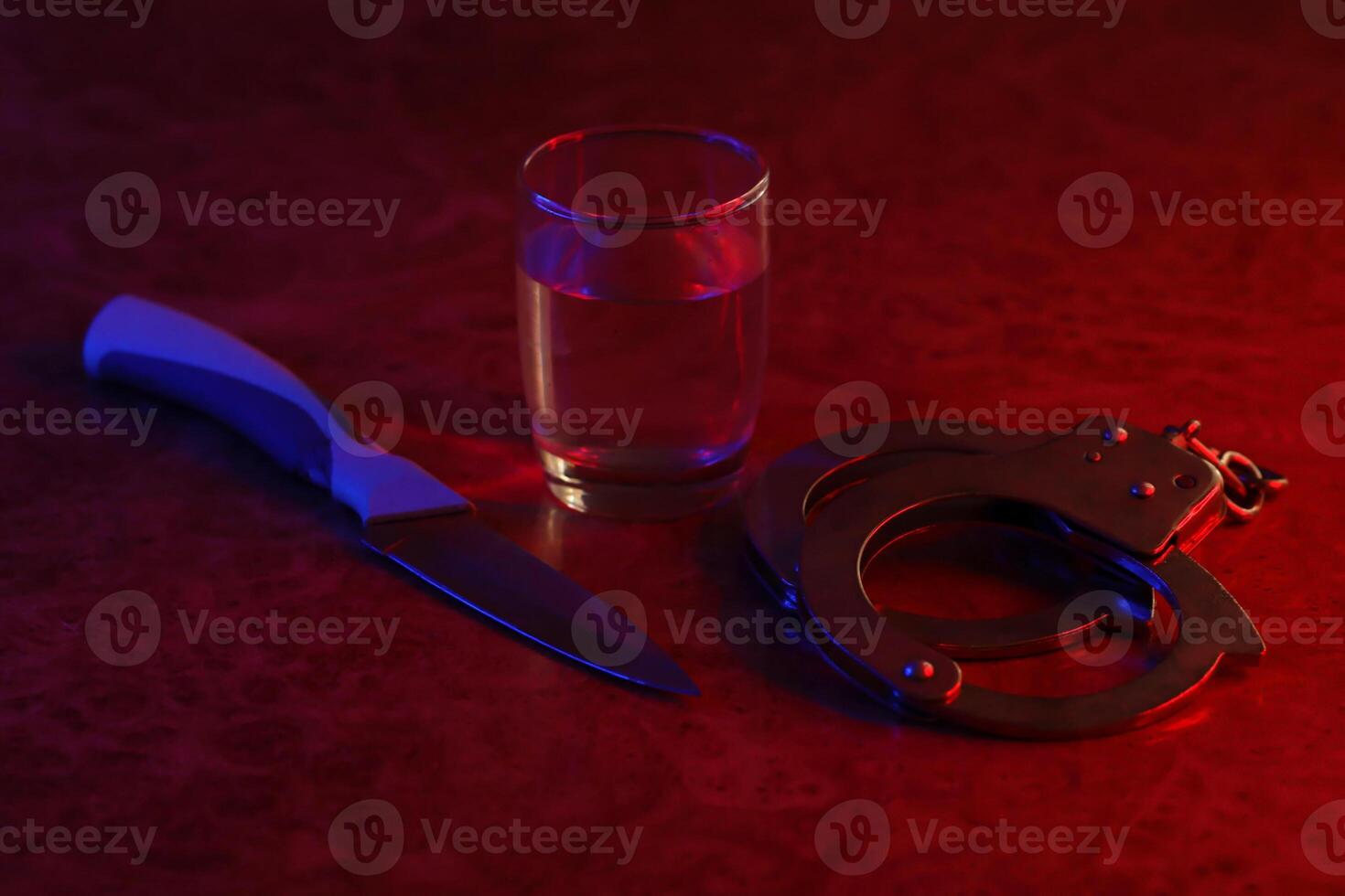 vaso con vodka alcohol beber, cuchillo y esposas. concepto de alcoholismo, delincuente foto