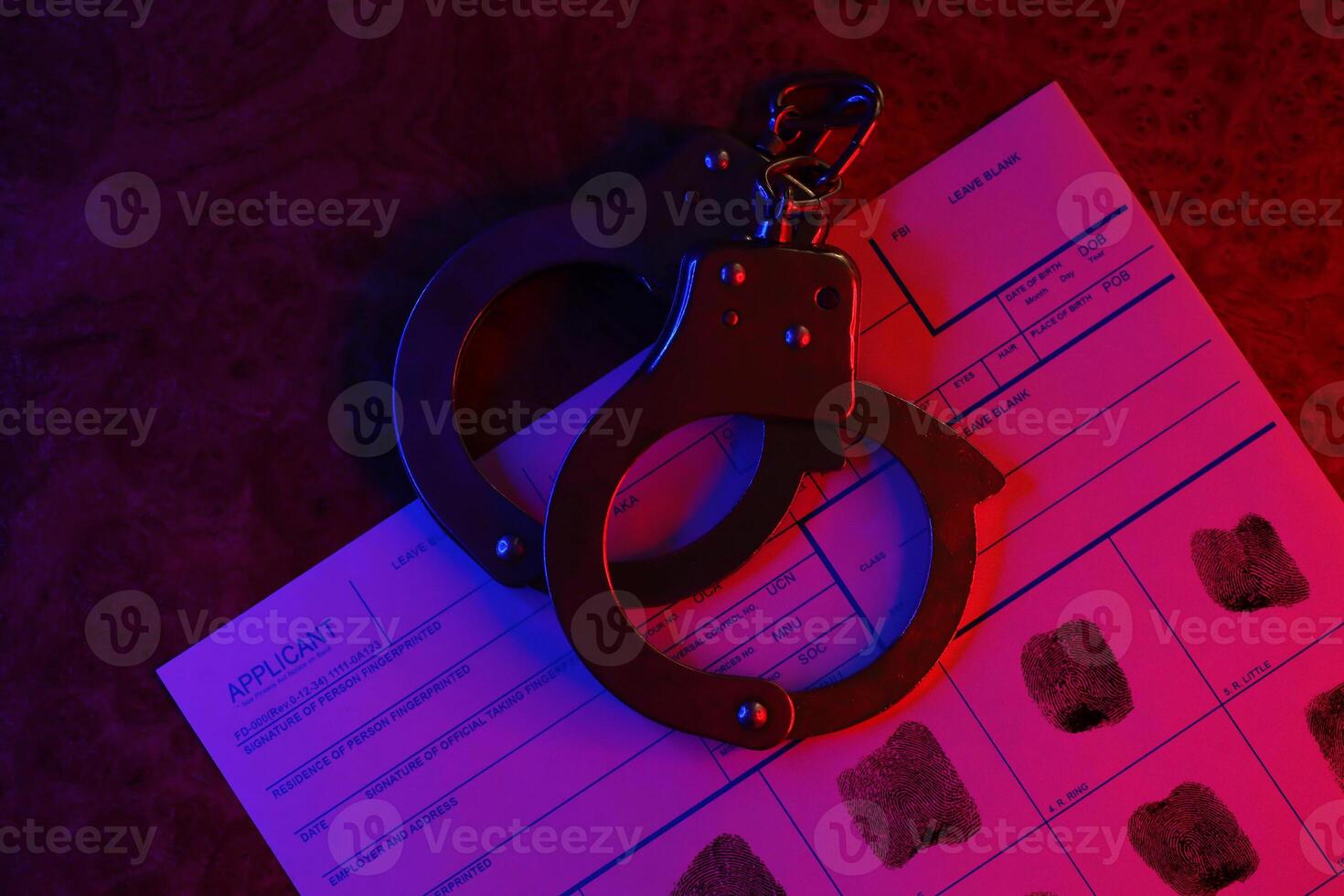 Applicant or fingerprints card with police handcuffs on table in dark room photo