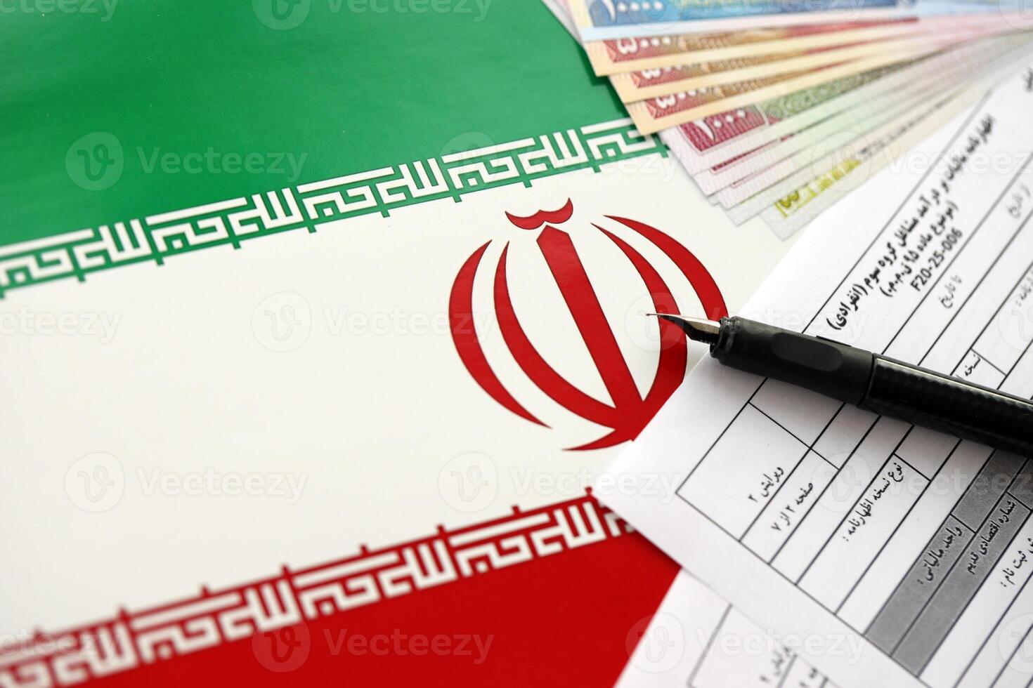 Iranian annual income tax return form F20-25-006 ready to fill on table with pen and iranian money on flag photo