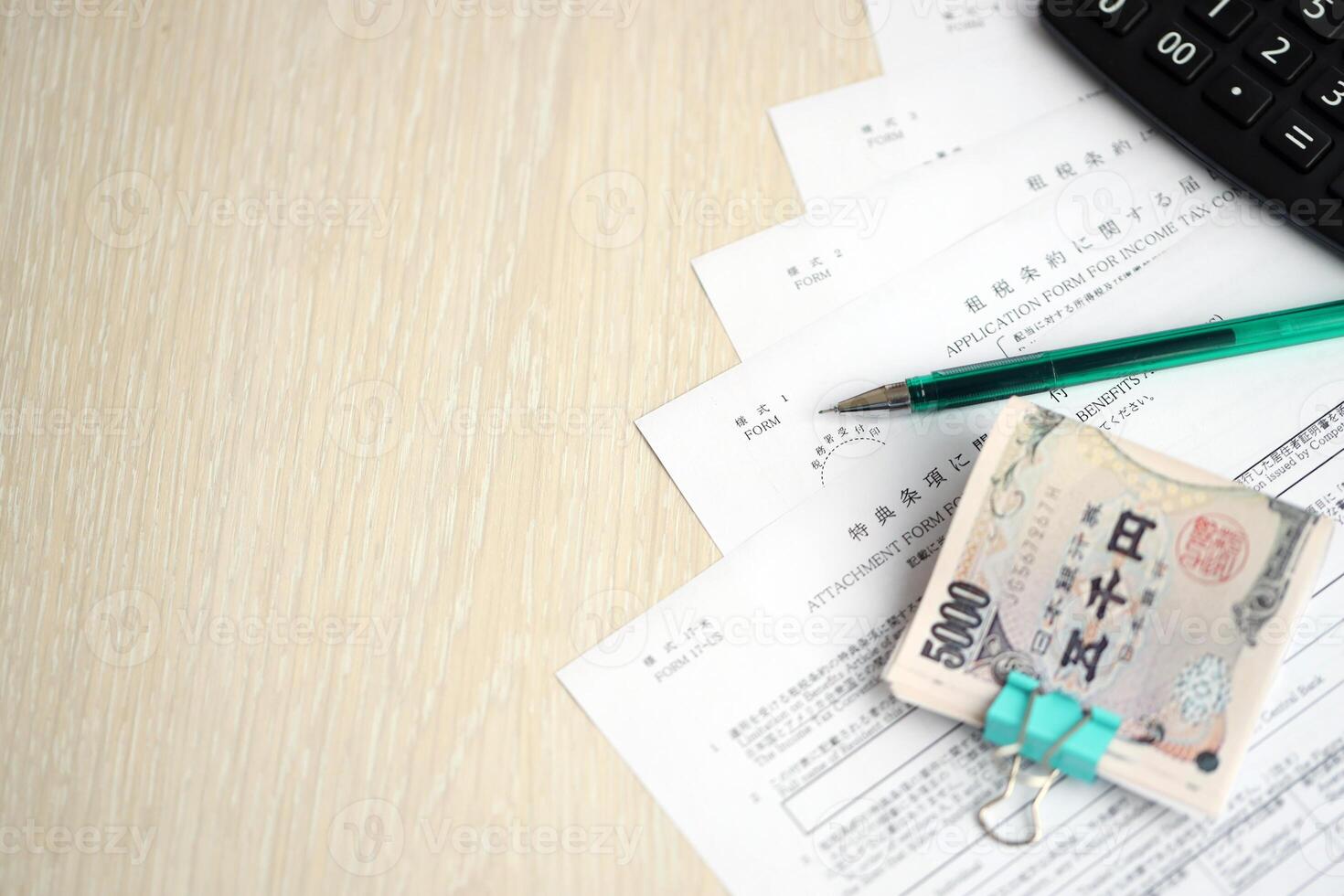 Japanese tax forms lies on table with calculator, pen and japanese yen money bills roll photo