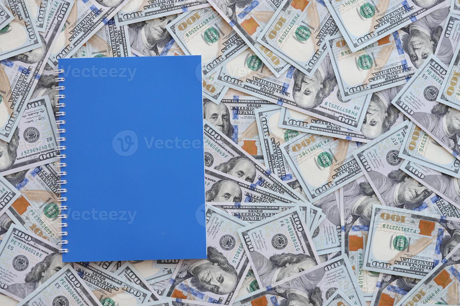 Office workplace table with blank notebook or notepad and many hundred dollar bills photo