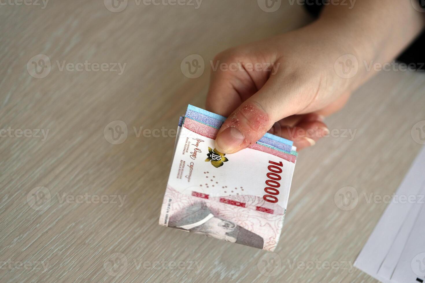 Female accountant hand give bunch of many indonesian rupiah money bills of new series photo