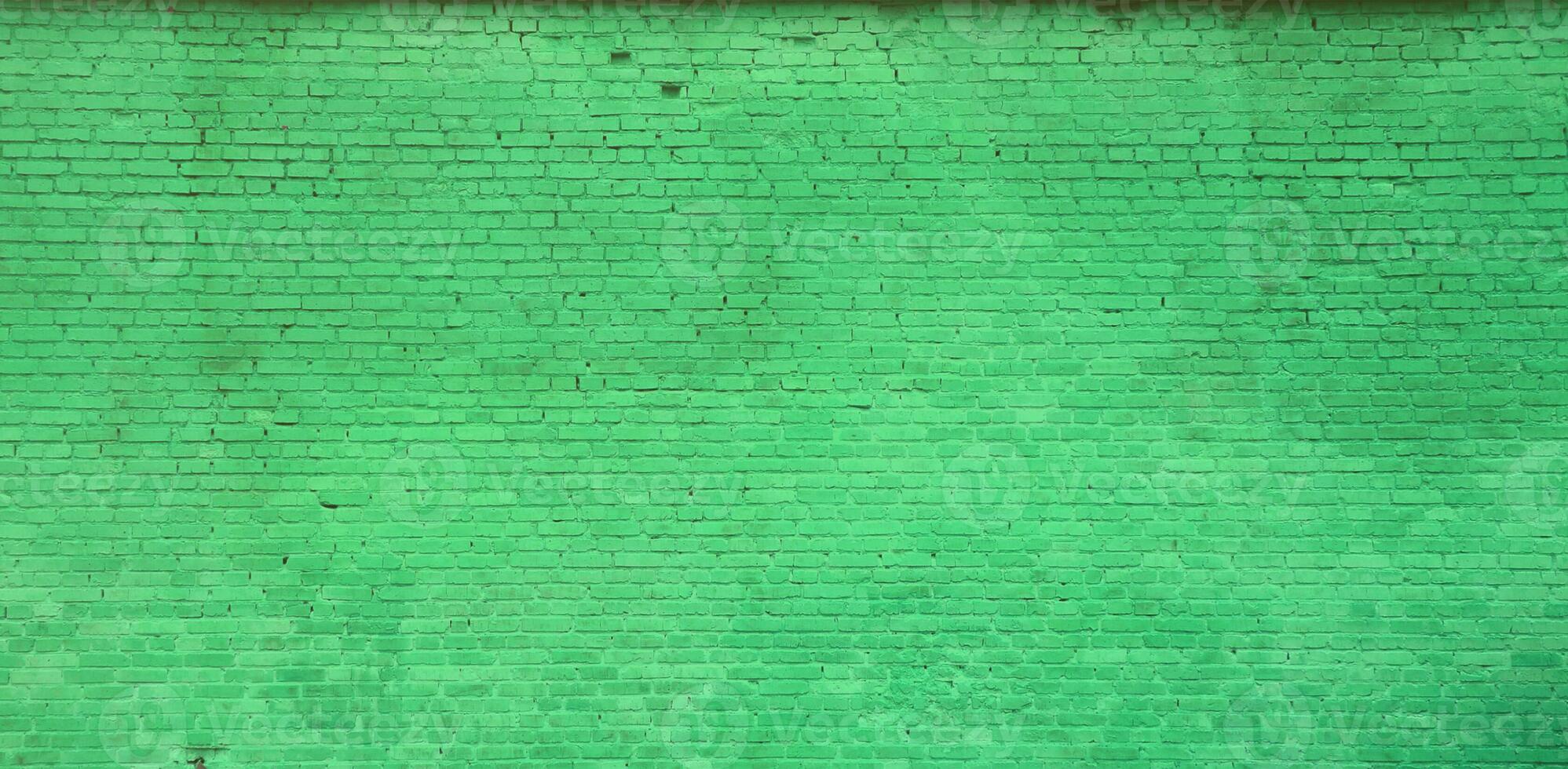 The texture of the brick wall of many rows of bricks painted in green color photo