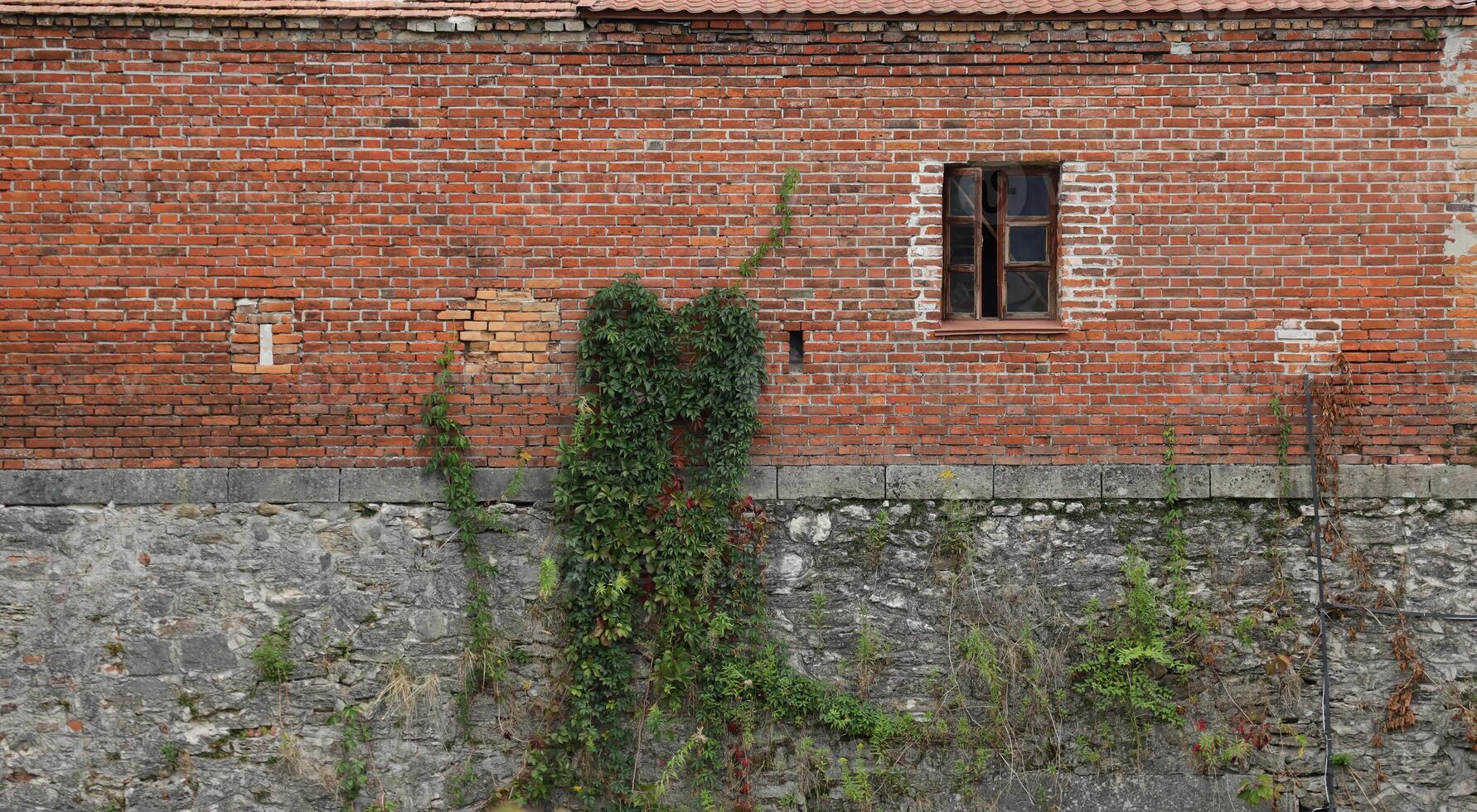 Very old brick stone wall of castle or fortress of 18th century. Full frame wall with obsolete dirty and cracked bricks photo