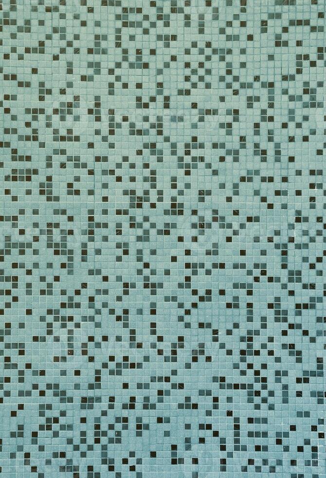 The texture of the wall, decorated with a mosaic of various small square tiles. Abstract pattern of ceramic tiles on the wall photo