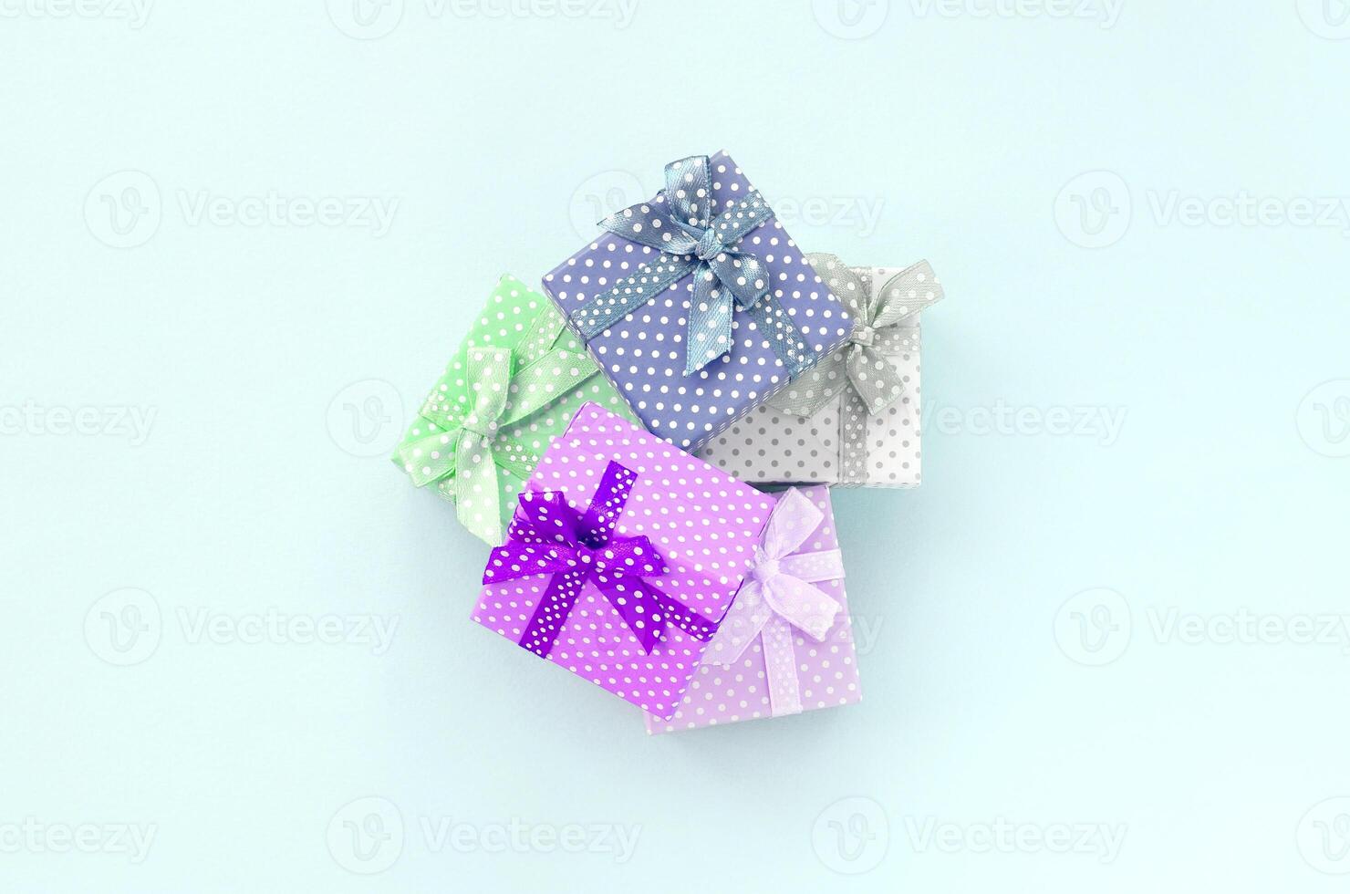 Pile of a small colored gift boxes with ribbons lies on a violet background. Minimalism flat lay top view photo