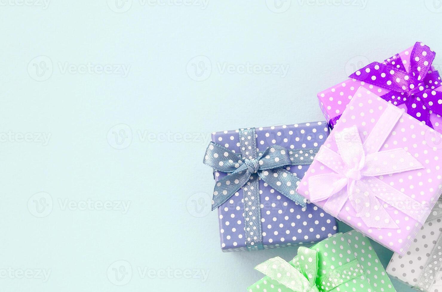 Pile of a small colored gift boxes with ribbons lies on a violet background. Minimalism flat lay top view photo