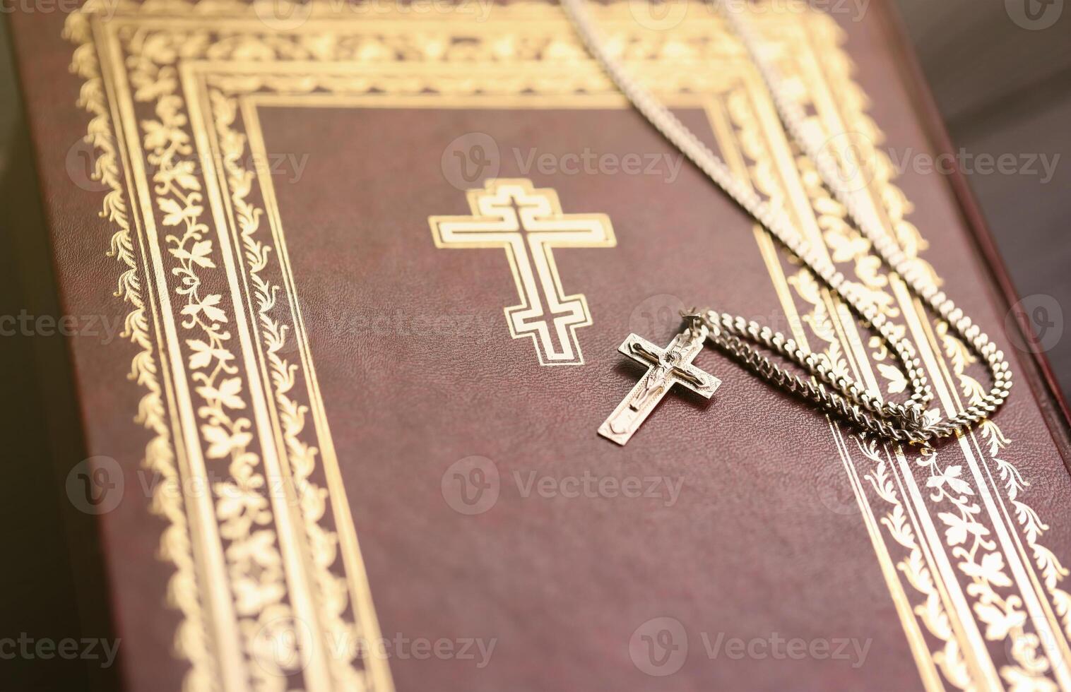 Silver necklace with crucifix cross on christian holy bible book on black wooden table. Asking blessings from God with the power of holiness, which brings luck photo