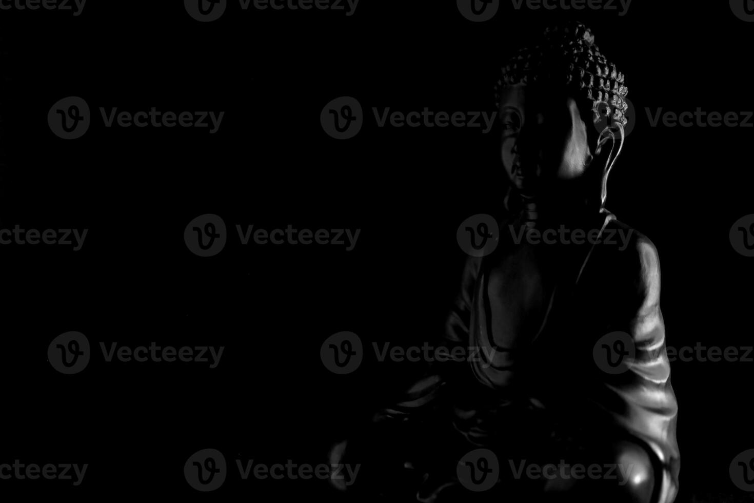 Buddha Purnima and Vesak day concept, Grey Buddha statue with low key light against deep black background photo