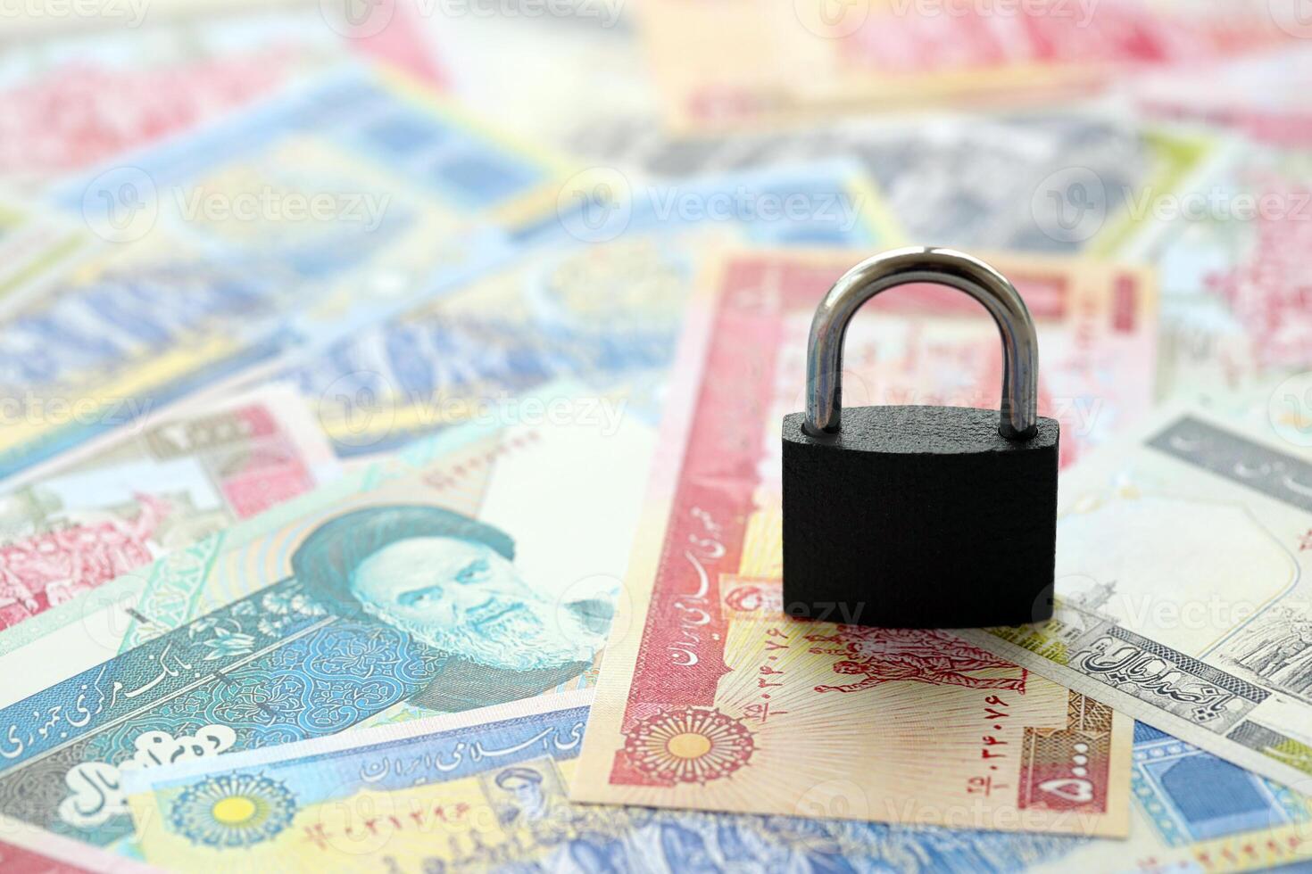 Small padlock lies on pile of iranian money. Sanctions, ban or embargo concept photo