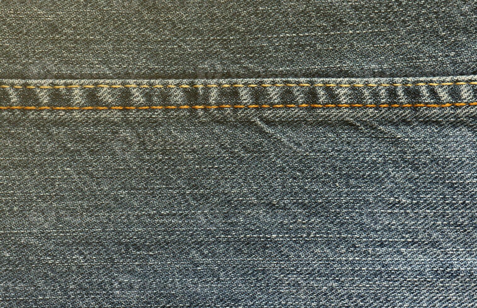 Detailed abstract texture of dark blue denim cloth. Background image of old used denim trousers fabric photo