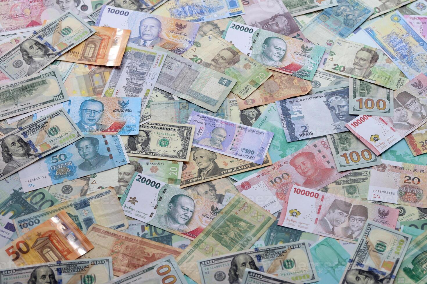 Many banknotes of different currency. Background of big amount of random money bills photo