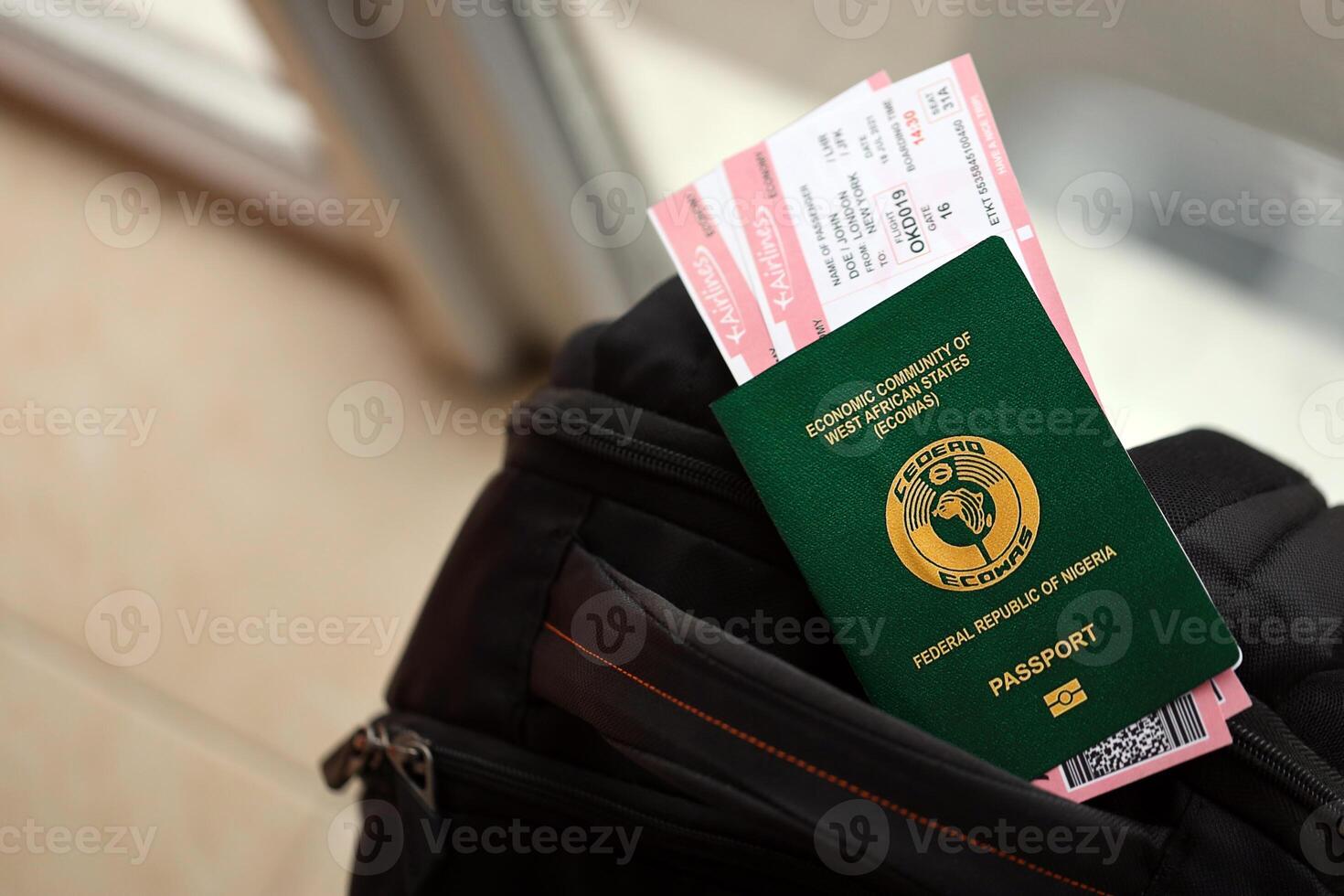 Green Nigerian passport with airline tickets on touristic backpack photo