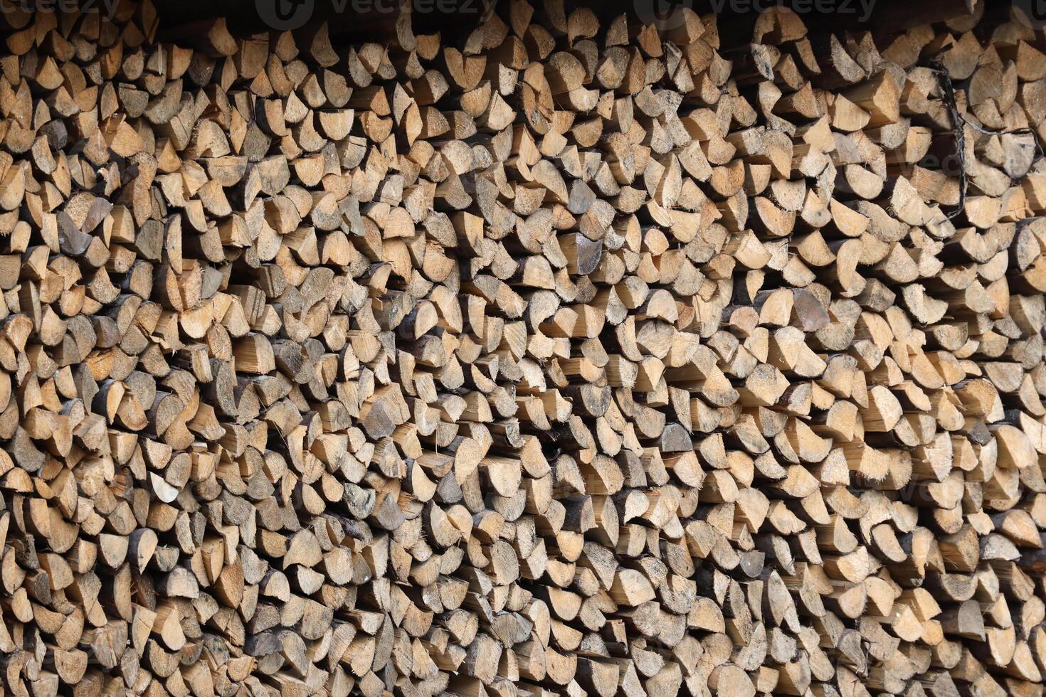 Firewood stacked near the wooden wall of old hut. Many chopped logs of firewood photo