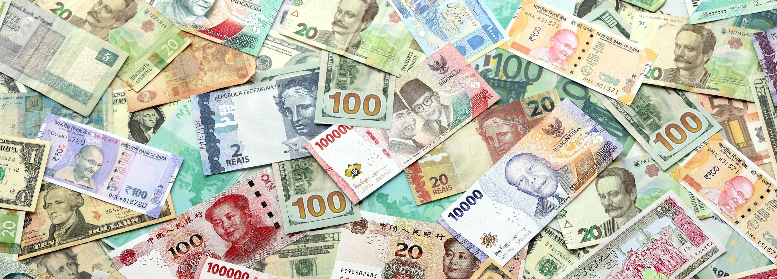 Many banknotes of different currency. Background of big amount of random money bills photo