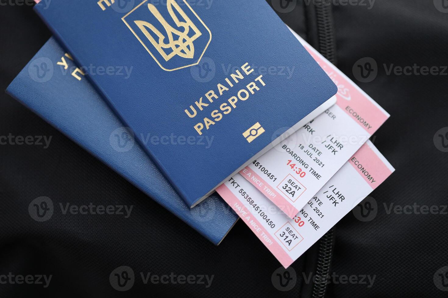 Two ukrainian biometrical passports with air flight tickets on black touristic backpack photo