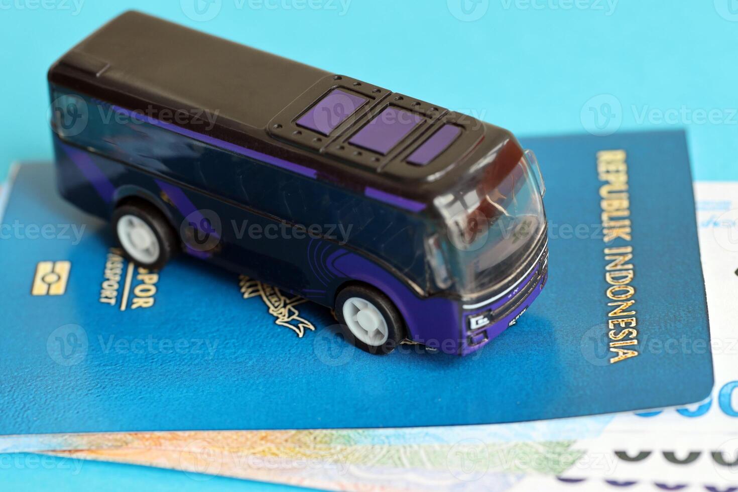 Blue Republic Indonesia passport with money and toy bus on blue background close up photo