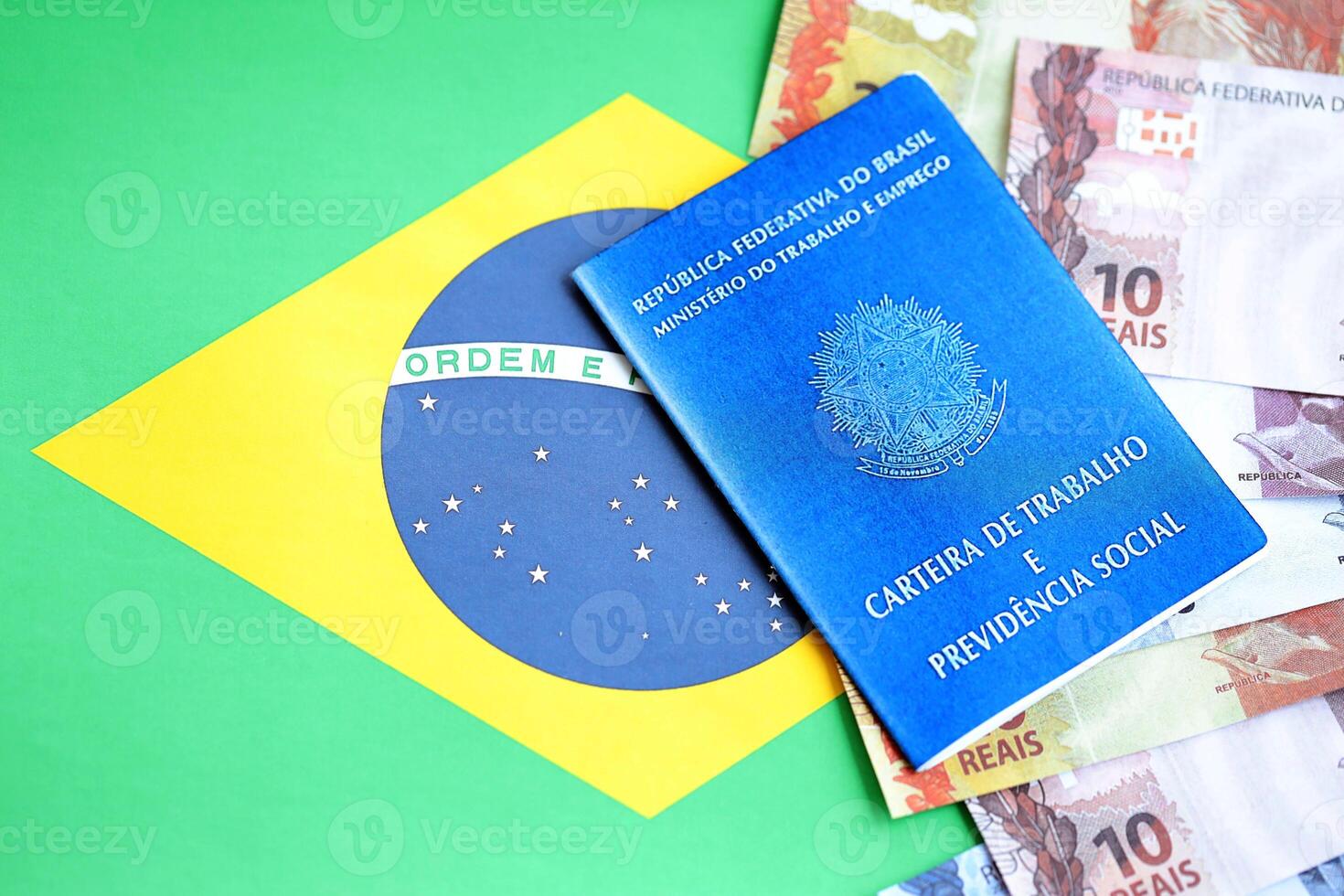 Brazilian work card and social security blue book and reais money bills on flag of Federative Republic of Brazil photo