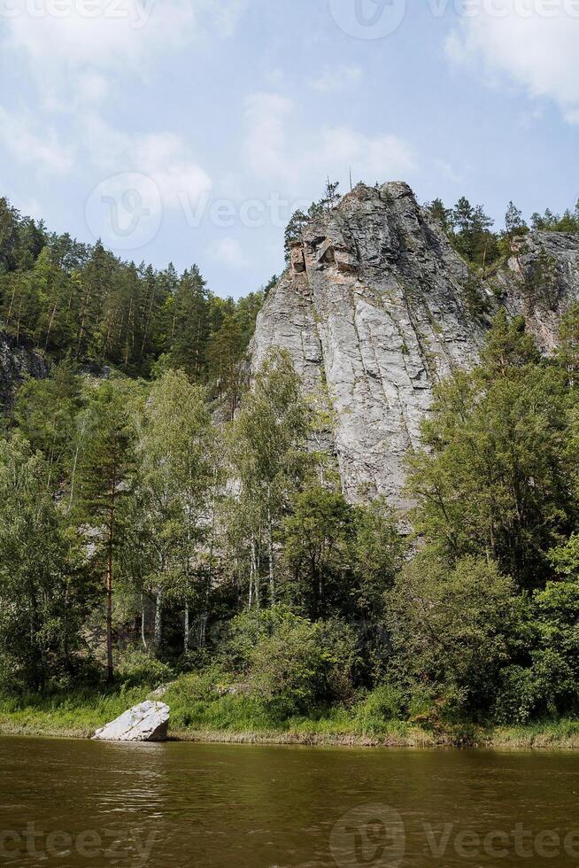 The rock peak rises above the water, the nature of central Russia, the mountain river in Siberia, calm water, the landscape of summer day. photo