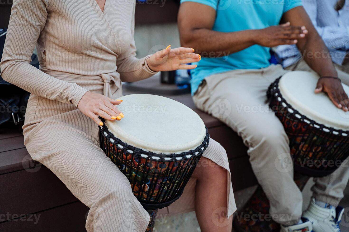 A beautiful girl plays the djemba, women's hands hit the drum, street performers, close-up. photo