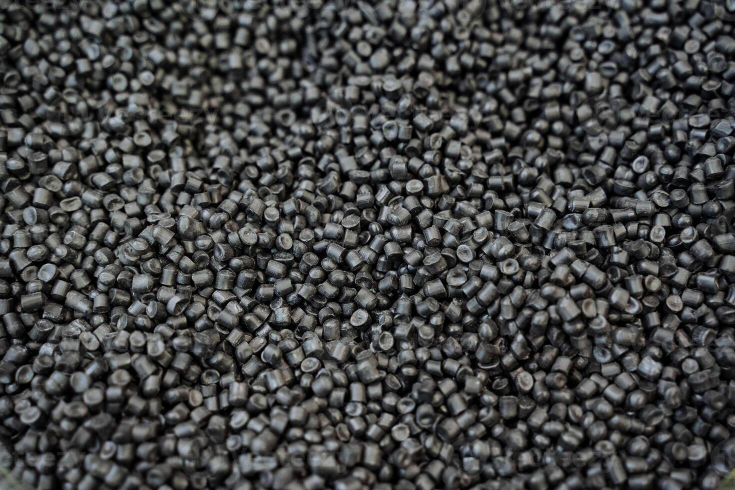 Black plastic chips are shot close-up, granules of polymeric material for the chemical industry, the structure of raw materials in a pile of small plastic. photo