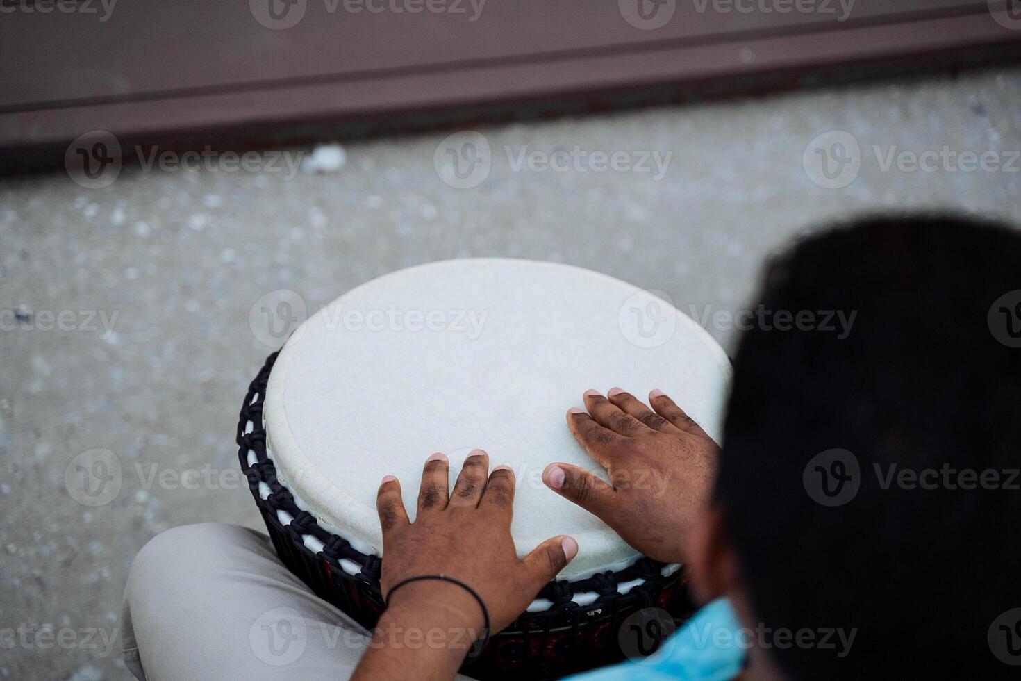 A guy from Africa drums on a djemba, the black hands of a man on a white deck, a percussion instrument, street music, an African-American performs on stage. photo