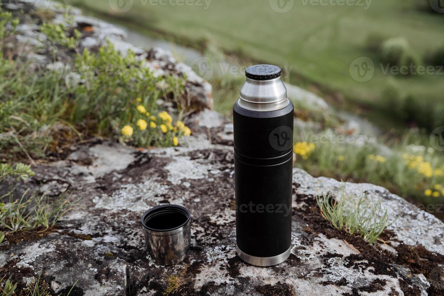 Drink tea in nature from a thermos, open lid, pour tea into a mug, hike in the mountains, camping in nature, tourist dishes, thermo bottle. photo