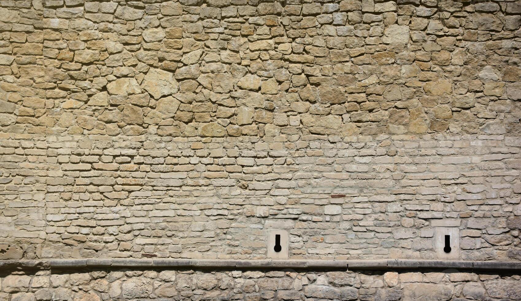 Very old brick stone wall of castle or fortress of 18th century. Full frame wall with obsolete dirty and cracked bricks photo