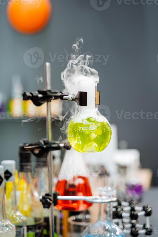 Chemical laboratory for wastewater treatment, experiments with gasoline filtration, smoke comes out of the flask, the green color of the combustible substance. photo