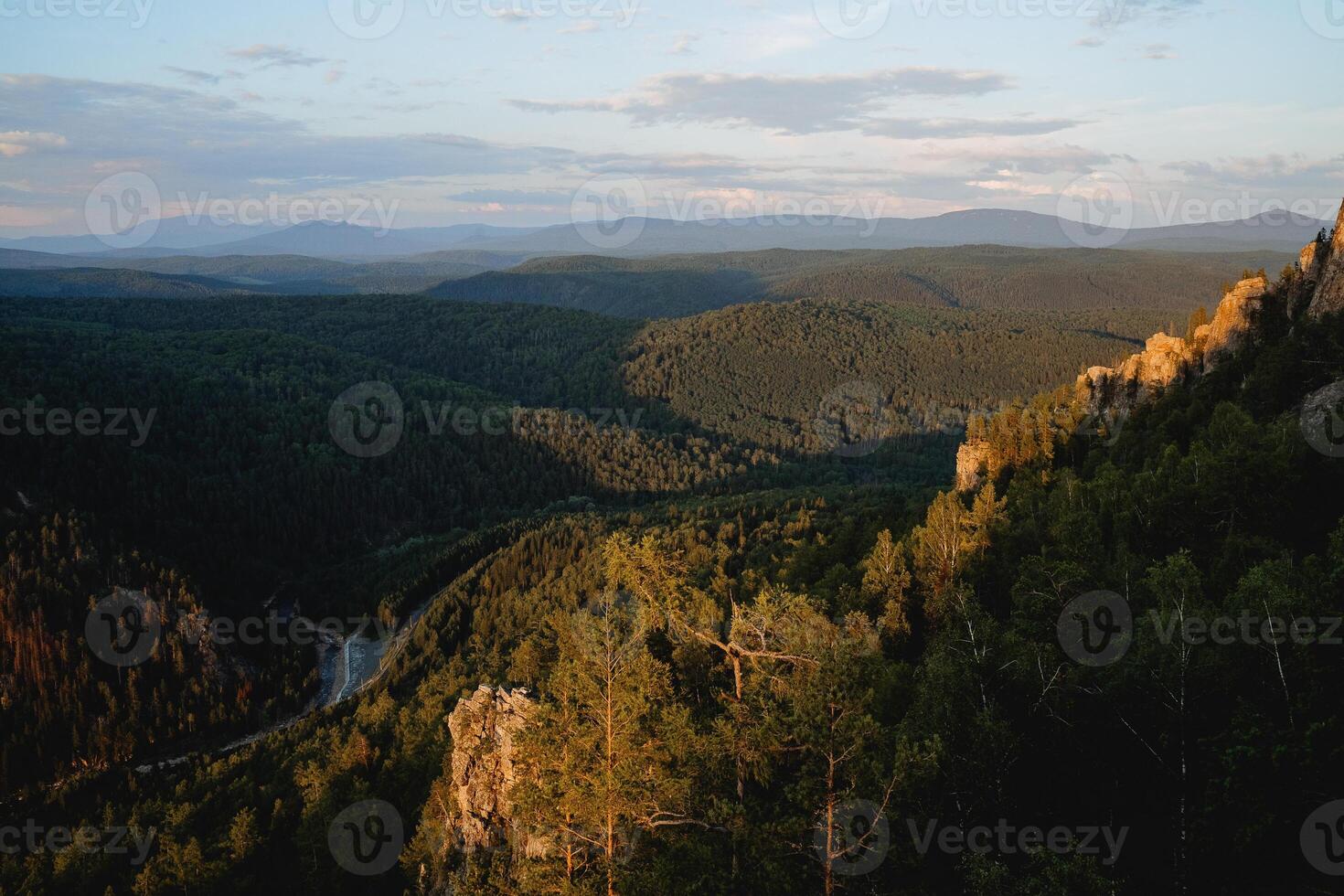 A beautiful landscape of mountains at sunset, the sun illuminates the tops of the trees, the panorama of the river valley, the misty haze over the forest. photo