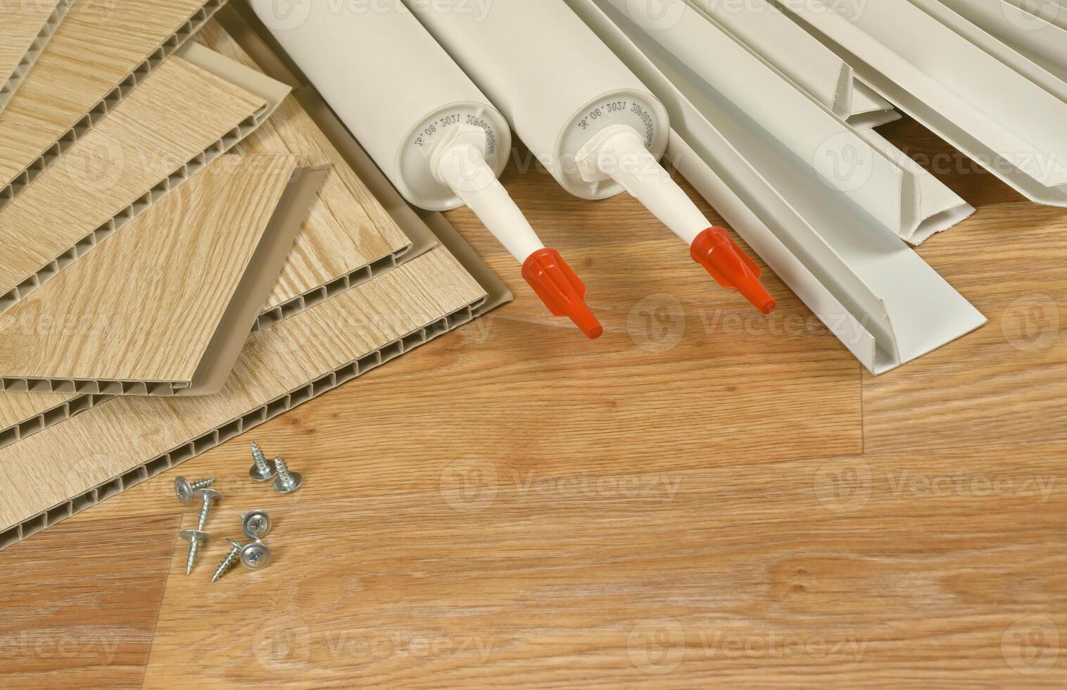 Set of items for PVC ceiling indoor works. Assembly adhesive bottles and PVC panels with plastic corners. Indoor VPC siding kit. Interior renovation works or construction photo