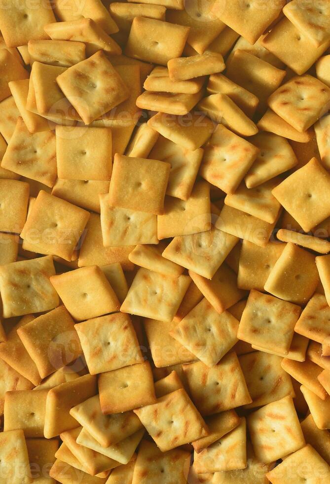 Background texture of small edible squares baked from dough and sprinkled with salt. A lot of salt cracker photo