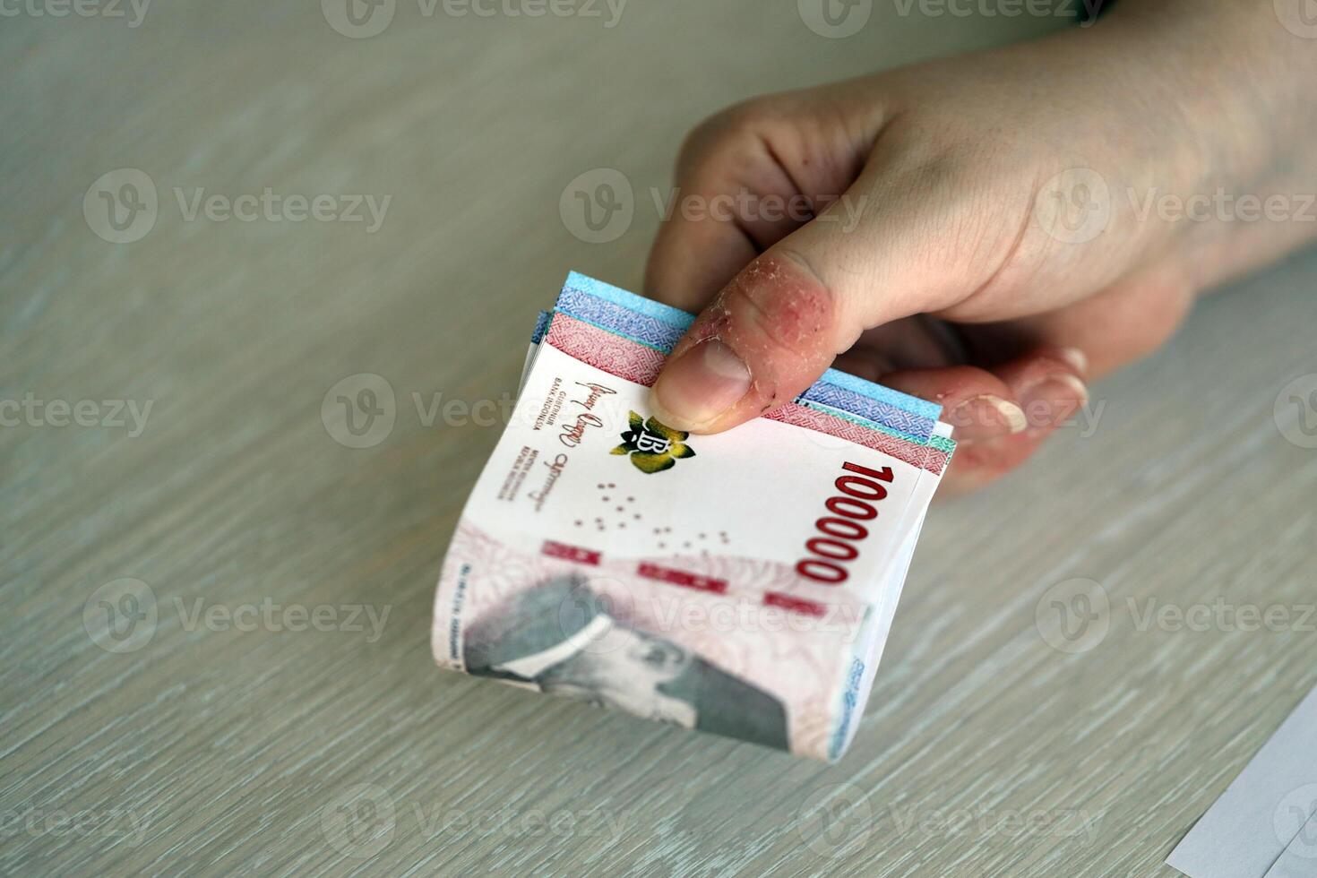 Female accountant hand give bunch of many indonesian rupiah money bills of new series photo
