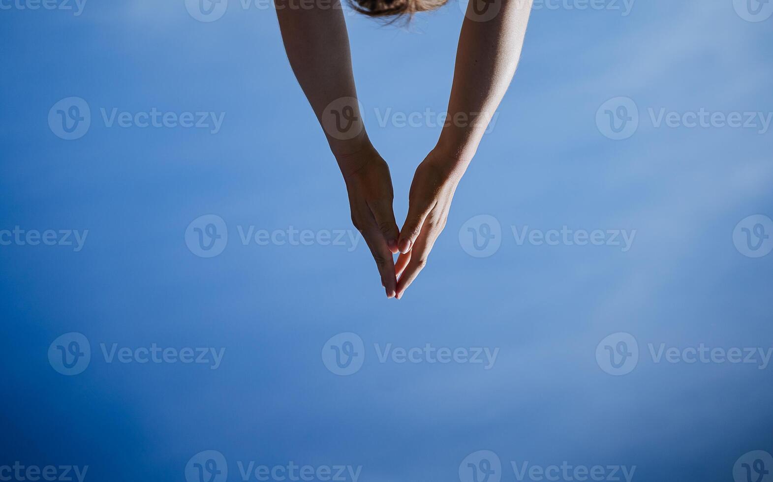 Hands reach for the sky, a triangle of human hands, body parts, blue sky, minimalism in life. photo