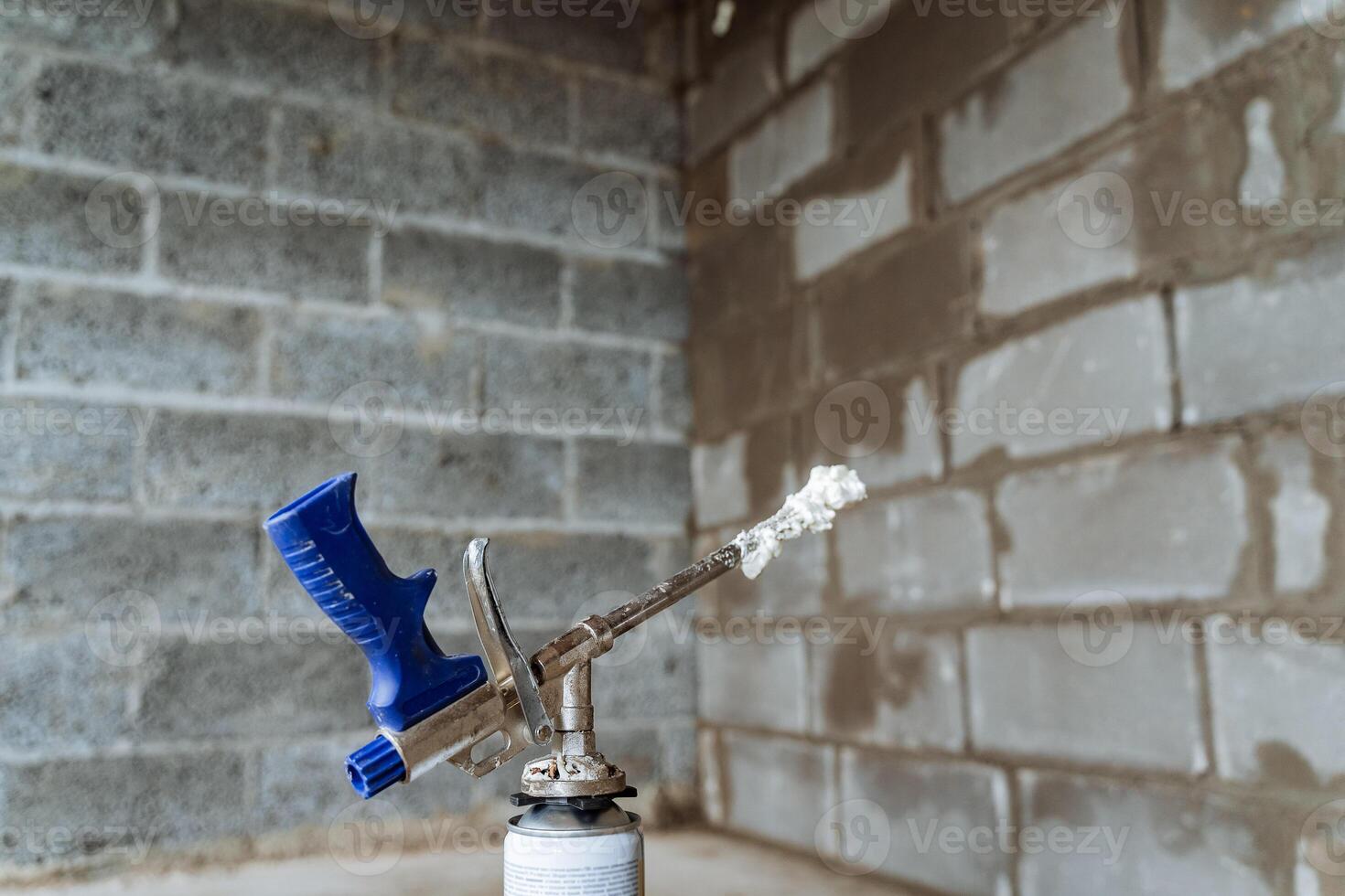 Construction gun emits spray foam, indoor construction, compressed air tool, steel foam tube. photo