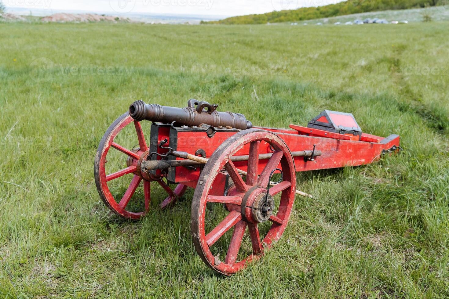 Medieval cannon, cast gun of the ancient world, Lithuanian artillery of the Middle Ages, red wooden wheels, historical object, museum exhibit. photo
